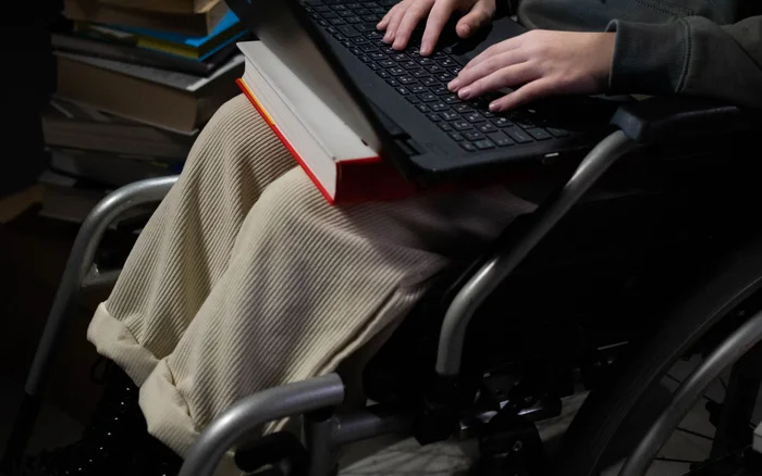 Person in a wheelchair using a laptop in a study setting
