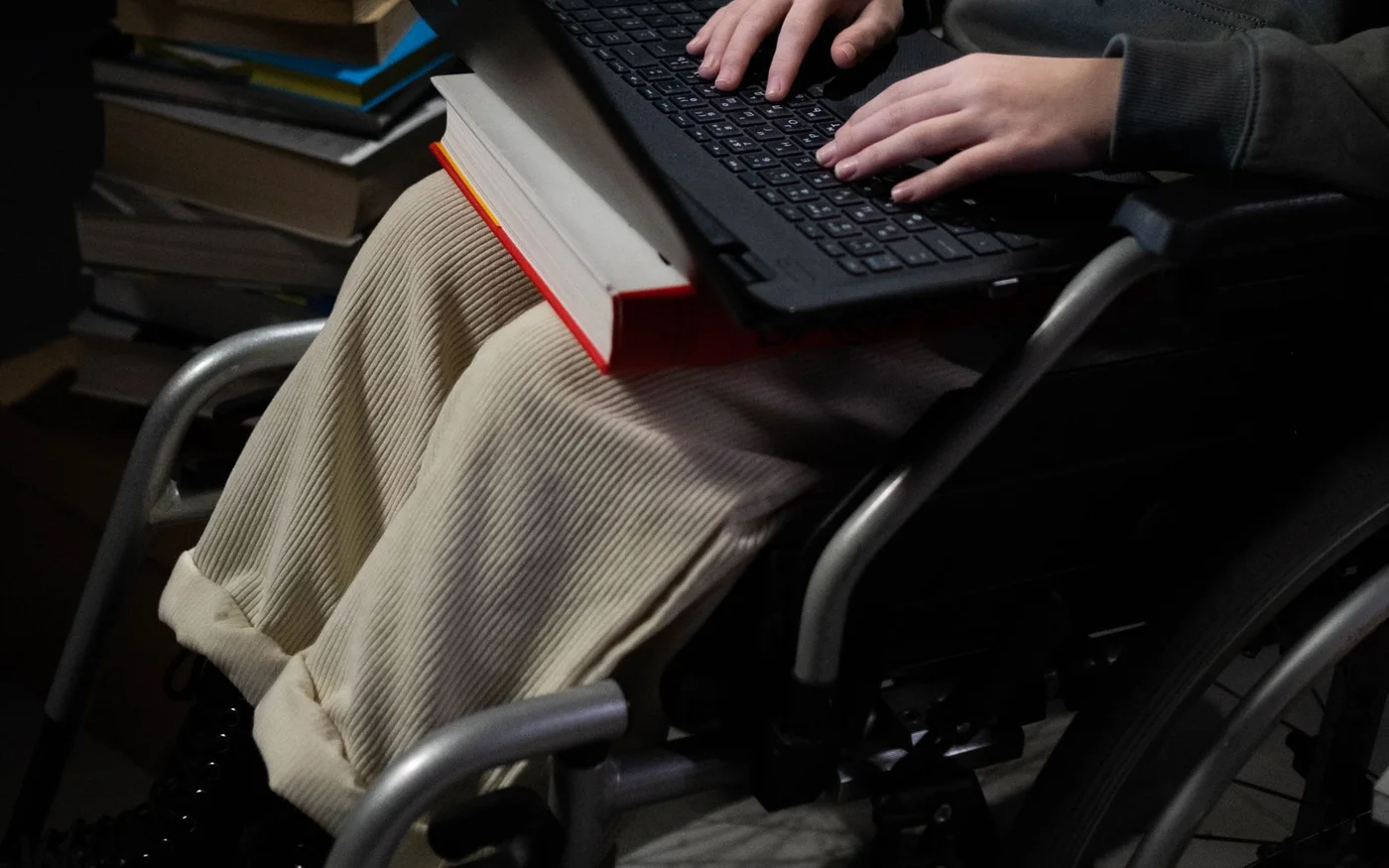 Person in a wheelchair using a laptop in a study setting