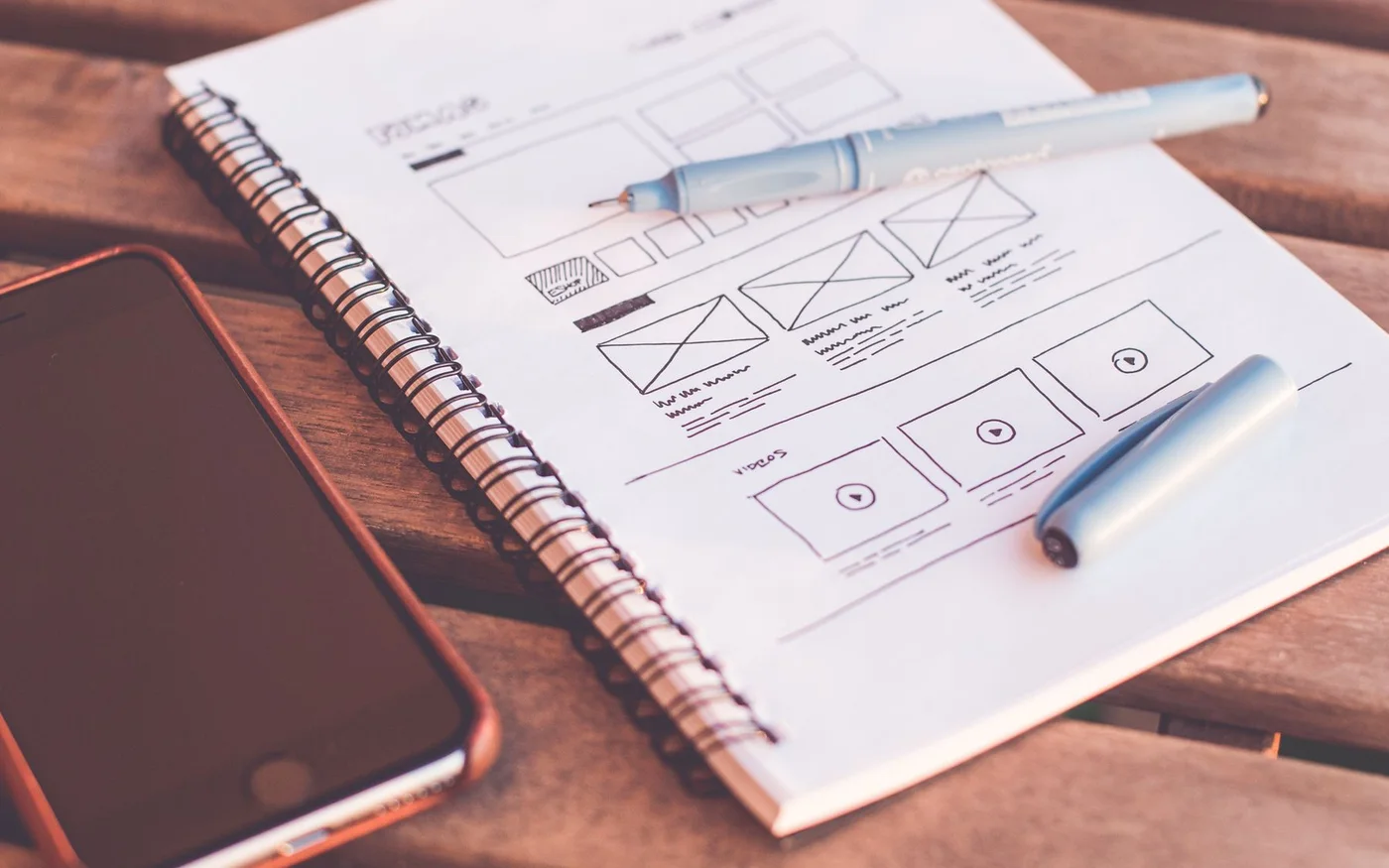 Notebook showing website wireframes beside a phone
